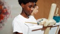 African boy painting canvas while girl draw cool tone picture. Edification. Royalty Free Stock Photo