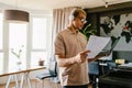 African business man reading paper documents while standing with laptop in office Royalty Free Stock Photo