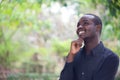 African business man thinking and smiling in green nature background Royalty Free Stock Photo