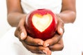 African business woman holding delicious red apple with cut heart