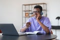 African businessman call on the phone, laptop and contract on desk in office room