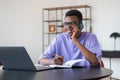 African businessman call on the phone, laptop and notebook on desk in office room