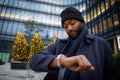 African businessman checks the time from his watch on a winter day