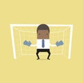 African businessman playing goalkeeper standing in front of goal.