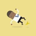 African businessman slipping on a banana peel and falling down.