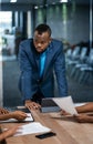 African businessman talking with a diverse group colleagues while having a meeting together around a table in an office boardroom