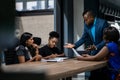 African businessman talking with a diverse group of female colleagues while having a meeting together around a table in an office Royalty Free Stock Photo
