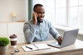 African Businessman Talking On Phone Sitting At Laptop In Office Royalty Free Stock Photo