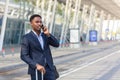 African businessman traveling near airport with suitcase calling taxi using mobile app Royalty Free Stock Photo