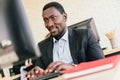 The African businessman typing keyboard and looking on the screen with a smile and happy mood at his desk workplace. Royalty Free Stock Photo