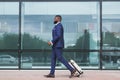 African businessman walking with luggage, arriving at airport