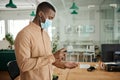 African businessman wearing a mask using hand sanitizer at work Royalty Free Stock Photo