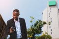 African businessman wears a black suit and uses a stylish smartphone with smile and happy