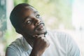 African businessman in white shirt looking out the window, thinking about workplace business problems.Black man sits and thinks Royalty Free Stock Photo