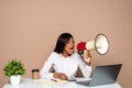 African businesswoman sitting at the table and shouting in megaphone on laptop Royalty Free Stock Photo