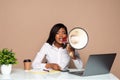 African businesswoman sitting at the table and shouting in megaphone on laptop Royalty Free Stock Photo