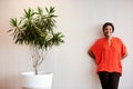 African businesswoman standing next to pot plant smiling at camera