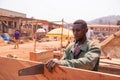 African carpenter in his open-air workshop sawing a board. Tiring handcraft Royalty Free Stock Photo