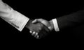 African and a caucasian man shaking hands over black background