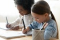 African and Caucasian schoolgirl mates sit at table writing task Royalty Free Stock Photo