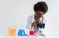 African child boy student researcher is afro hair wear lab coat and glasses standing looking through microscope while learning Royalty Free Stock Photo