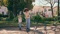 African child feeding birds with mother in park. Girl throwing food to pigeons. Royalty Free Stock Photo