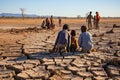 African children sit on soil cracked due to drought. Environmental problem of climate change, global warming, water shortage Royalty Free Stock Photo