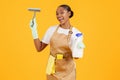 African cleaner lady holding detergent bottle and squeegee, studio shot