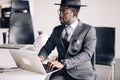 African confident businessman in suit and glasses working on laptop