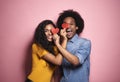 African couple covering eyes by hearts in studio shot