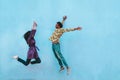 African couple jumping outdoor with blue wall in background - Crazy happy latin people having fun together - Youth, friendship and Royalty Free Stock Photo