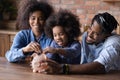 African couple with little daughter putting coins into piggy bank Royalty Free Stock Photo