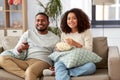 African couple with popcorn watching tv at home