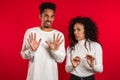 African couple on red showing disgust, aversion gesture at camera. Royalty Free Stock Photo