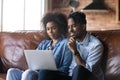 African couple sit on sofa with wireless computer buying online Royalty Free Stock Photo