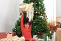African curly hair girl child lifts up gift box during sits on floor surround with many presents under decorative Christmas tree.