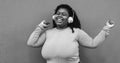 African curvy girl having fun dancing and listening music with headphones outdoor - Focus on face - Black and white editing Royalty Free Stock Photo