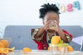 African cute kid girl drinking fresh oranges juice from glass at home for breakfast after making freshly squeezed orange juice on Royalty Free Stock Photo