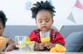 African cute kid girl drinking fresh oranges juice from glass at home for breakfast after making freshly squeezed orange juice on Royalty Free Stock Photo