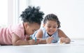 African cute little kid girl have fun drawing on paper while lying on floor with sister. Adorable happy children drawing Royalty Free Stock Photo