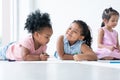 African cute little kids girls have fun drawing on paper while sitting and lying on the floor with friends. Adorable happy Royalty Free Stock Photo