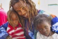 African dad with his two children on knee looking at camera. Father smiling, child shy Royalty Free Stock Photo