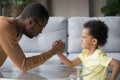 African dad and kid son with funny angry faces armwrestling Royalty Free Stock Photo