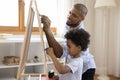 African dad and little son draw on chalkboard with chalks