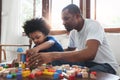 African Dad and son sitting playing colourful wood blocks toy together Royalty Free Stock Photo