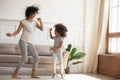 African daughter and mother dancing in modern living room Royalty Free Stock Photo