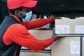 African delivery man loading boxes in the truck while wearing face mask to avoid corona virus spread Royalty Free Stock Photo