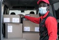African delivery man loading boxes in van truck while wearing face mask to avoid corona virus spread Royalty Free Stock Photo