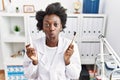 African dentist woman holding electric toothbrush and normal toothbrush puffing cheeks with funny face Royalty Free Stock Photo