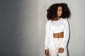 Freestyle. African girl in white outfit with bare belly standing isolated on gray looking aside pensive Royalty Free Stock Photo